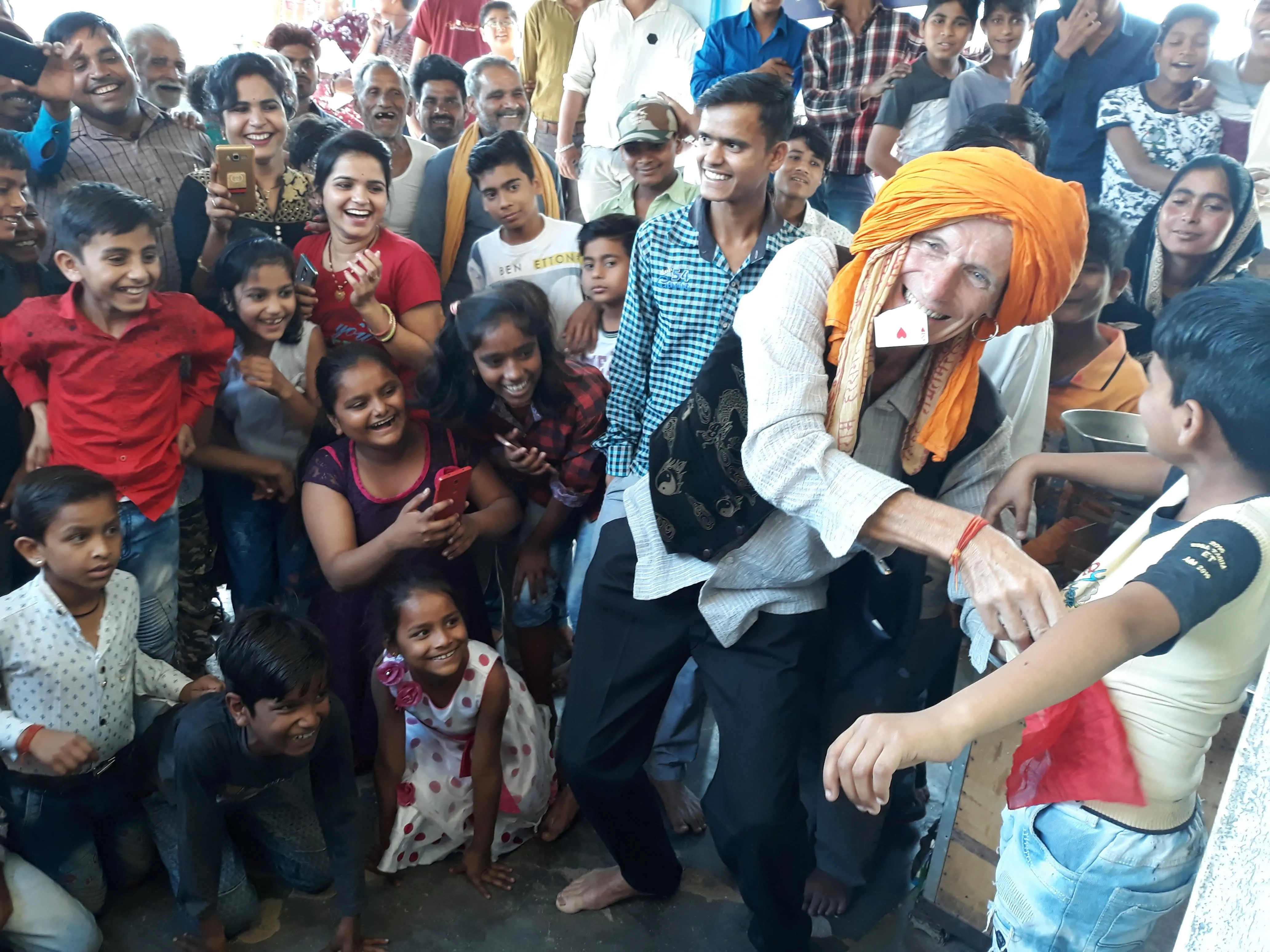 Sylvain le magicien, turban orange, entouré d'une nuée d'enfants rieurs pendant un spectacle